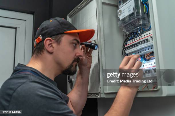 electricista utiliza linterna para reparar la caja de fusibles - electrical panel box fotografías e imágenes de stock