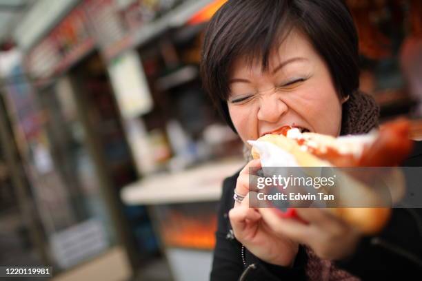 an asian chinese woman enjoying her local czech food in prague downtown - sausage patty stock pictures, royalty-free photos & images