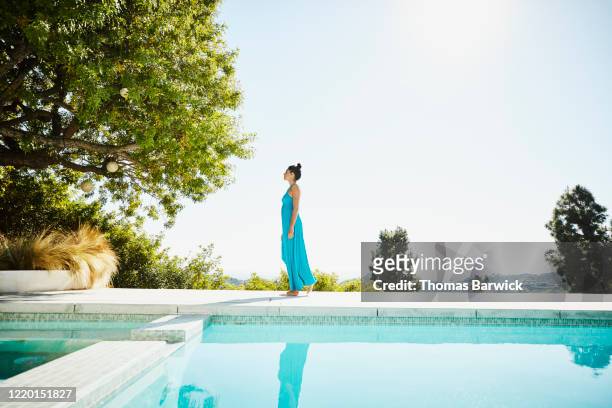 woman walking on pool deck of vacation home - long dress stock-fotos und bilder