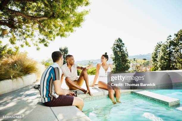 friends relaxing by pool of vacation rental - calções azuis imagens e fotografias de stock