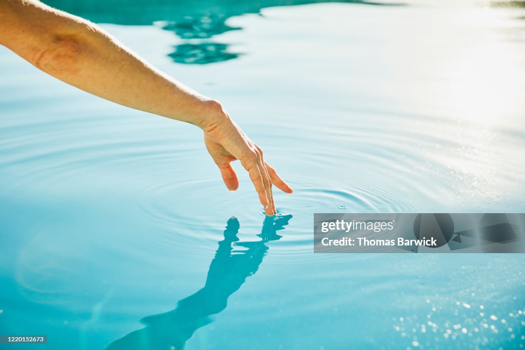 Womans hand touching surface of water