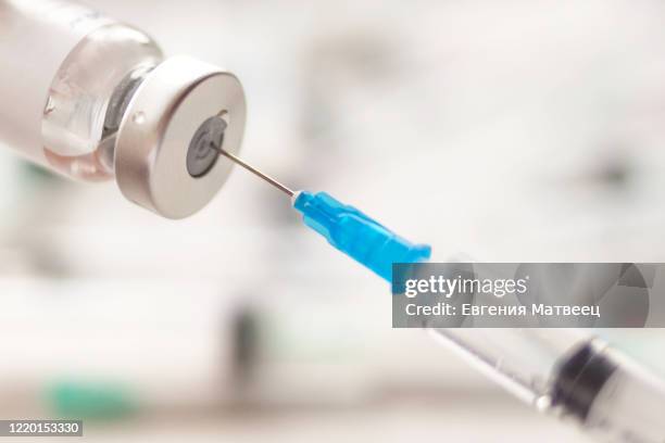 dialing medicine into syringe from glass bottle. ampoule and syringe needle close-up. - injecting foto e immagini stock