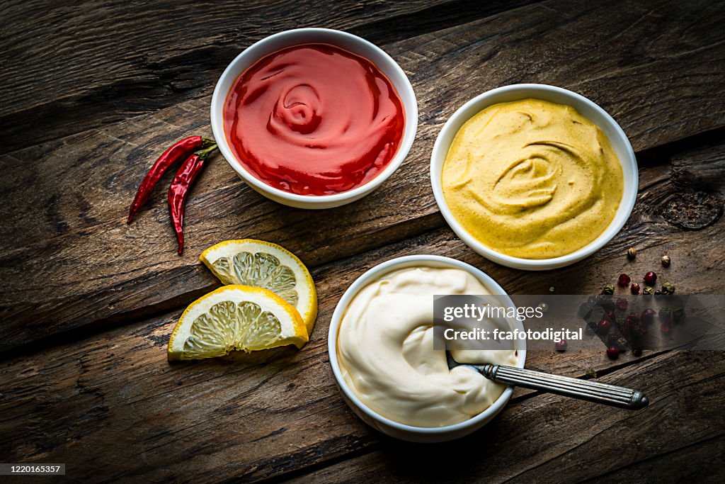 Ketchup, mustard and mayonnaise on rustic wooden table
