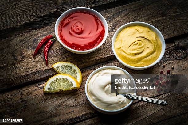 ketchup, mustard and mayonnaise on rustic wooden table - sauce stock pictures, royalty-free photos & images