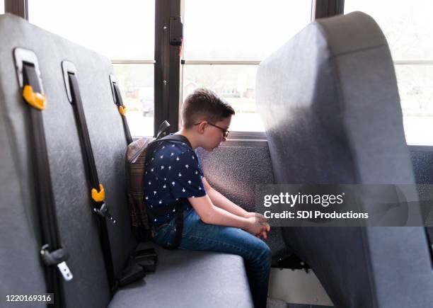 elementary age boy sits alone on bus; thinks about day - school bus interior stock pictures, royalty-free photos & images