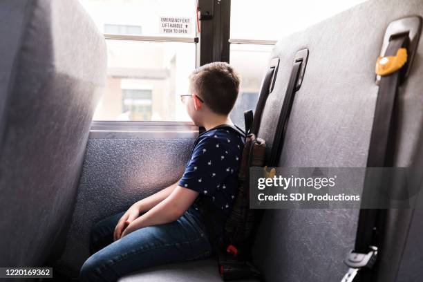 elementary age boy sits alone on school bus - unhappy school child stock pictures, royalty-free photos & images