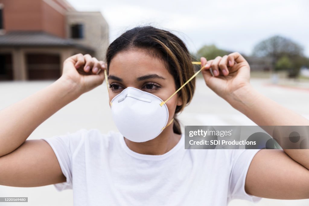 Mid adult female places N95 mask on face