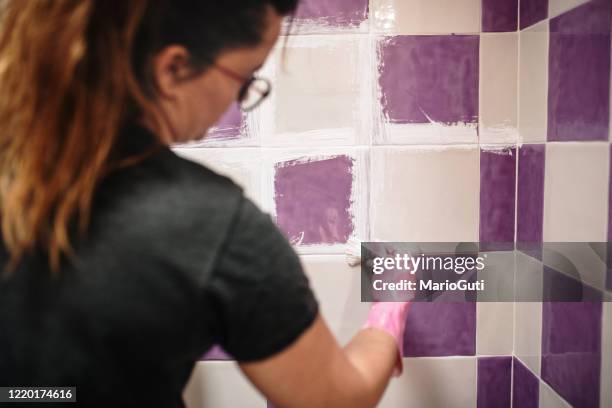 young woman painting her bathroom tiles white - bathroom tiles stock pictures, royalty-free photos & images