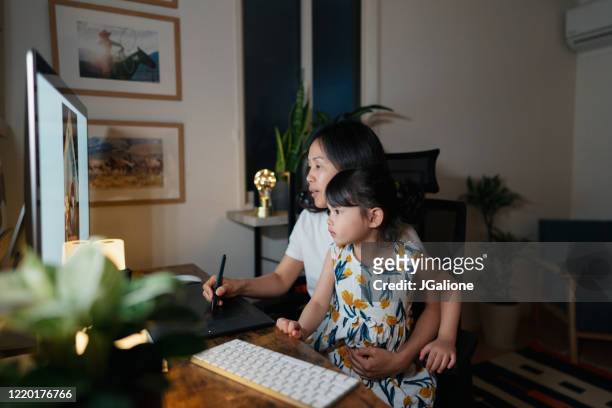 Mother working from her home office at night with her daughter