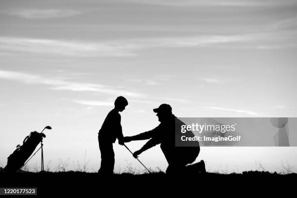 silhouette von jungen junior golfer immer eine lektion von seinem vater - golftraining stock-fotos und bilder