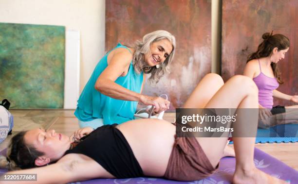 schöne reife doula mit natürlichen grauen haaren untersucht eine schwangere frau - prenatal class stock-fotos und bilder