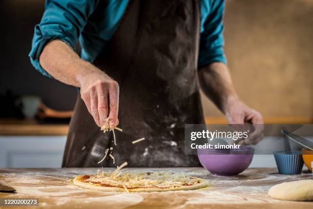 chef adding grated cheese on dough - man grating cheese stock pictures, royalty-free photos & images