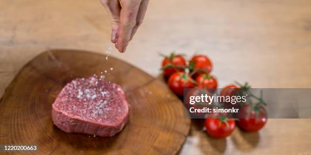 chef adding salt to meat - adicionar sal imagens e fotografias de stock