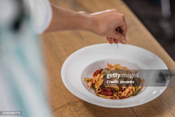 chef adding salt to pasta - personal chef stock pictures, royalty-free photos & images