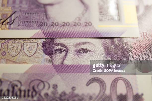 In this photo illustration banknotes of the pound sterling, The Bank of England £20 notes with the image of Queen Elizabeth II are seen displayed.