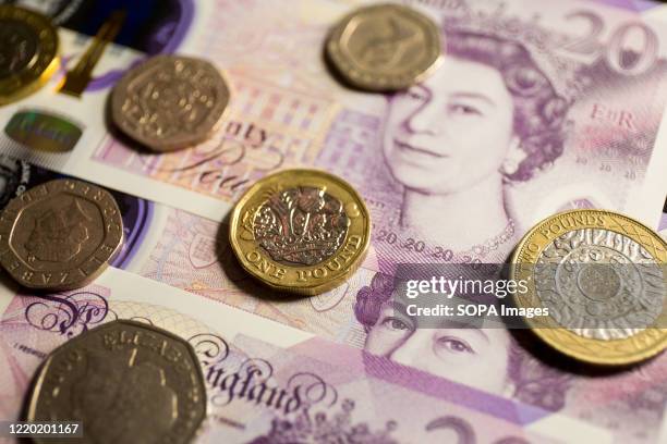 In this photo illustration banknotes of the pound sterling, The Bank of England £20 notes with the image of Queen Elizabeth II and various coins of...