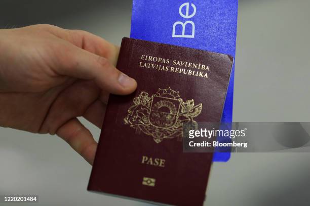 Traveler holds their Latvian passport and flight tickets as European Union travel restrictions are lifted at Berlin Shoenfeld Airport in Schoenefeld,...
