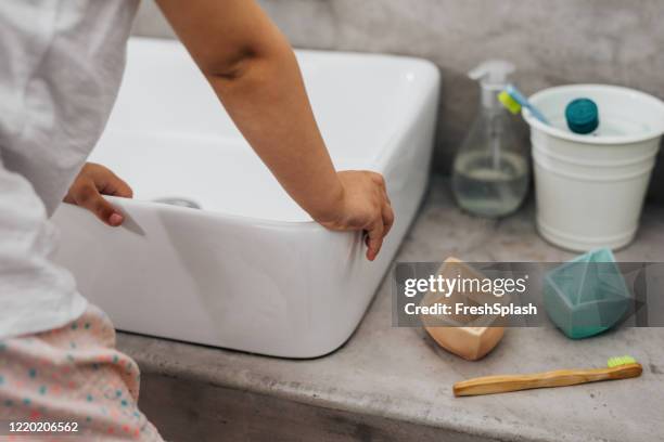 mains d’une fille restant par le évier de salle de bains prêt pour l’hygiène de matin - bassine photos et images de collection