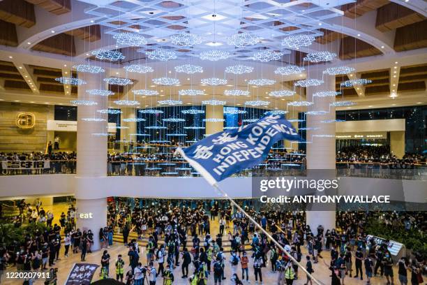 People wave flags and shout slogans inside a shopping mall to mark the one year anniversary of a man who fell to his death after hanging a protest...