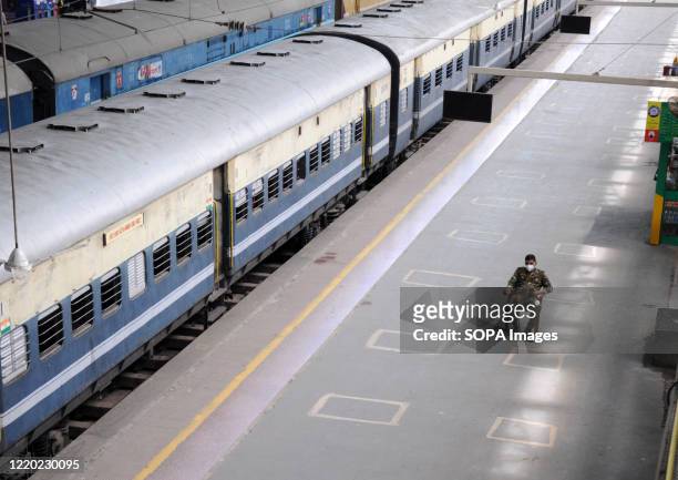 Security personnel sitting along a railway platform while wearing a face mask as a preventive measure during the Coronavirus crisis. Local suburban...