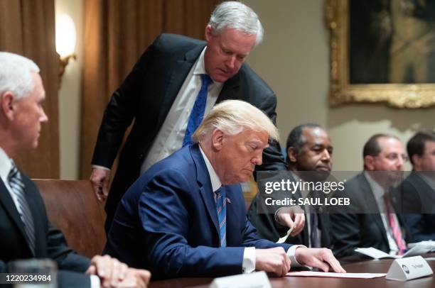 White House Chief of Staff Mark Meadows hands a note to US President Donald Trump during a roundtable meeting on seniors in the Cabinet Room at the...