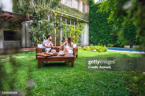 young couple enjoying relaxing breakfast in backyard - outdoor chair stock pictures, royalty-free photos & images