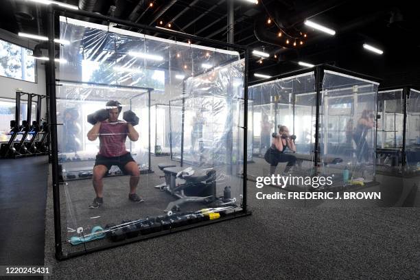 People exercise at Inspire South Bay Fitness behind plastic sheets in their workout pods while observing social distancing on June 15, 2020 in...