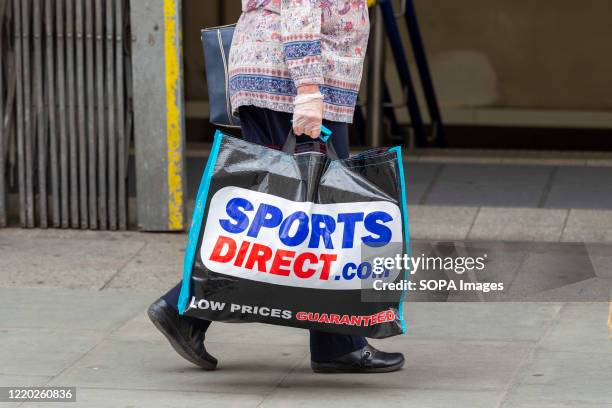 Woman carries a Sports Direct shopping bag on Londons Oxford Street after the shops were allowed to reopen.