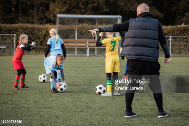 padre de fútbol entrenando equipo de la hija de fútbol durante una sesión de entrenamiento - subs bench fotografías e imágenes de stock