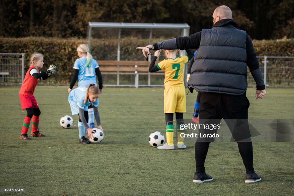 Soccer father coaching football daughter's team during a training session