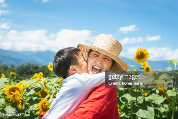 母と息子は太陽の花畑でリラックス - 子供　日本人　笑顔 ストックフォトと画像