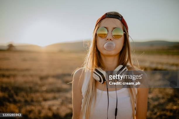 adolescente che fa palloncino di gomma da masticare in una soleggiata giornata estiva - musica pop foto e immagini stock