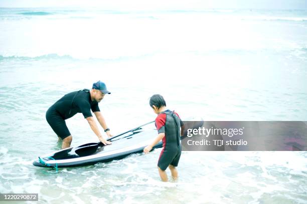 father and son  paddle surfing - paddleboarding team stock pictures, royalty-free photos & images