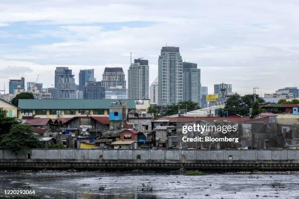 Homes in the San Roque neighborhood stand along the waterfront as commercial and residential high-rise buildings stand in the background in Quezon...