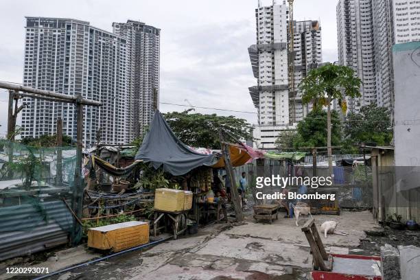 People gather in the San Roque neighborhood as commercial high-rise buildings stand in the background in Quezon City, Metro Manila, the Philippines,...