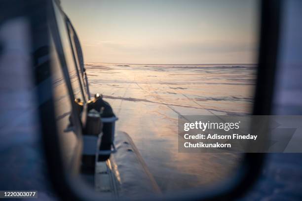 a beautiful sunset reflected in the mirror of a distant view of the car on lake baikal in winter. - sibirien bildbanksfoton och bilder