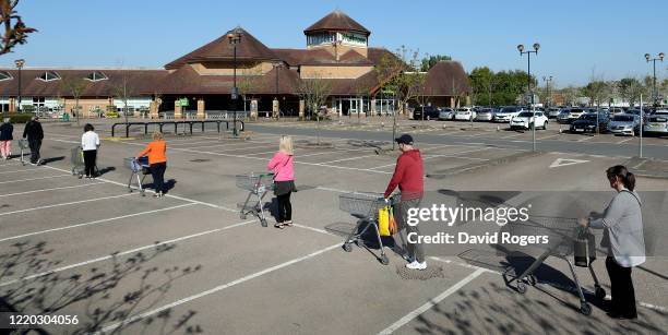 Shoppers queue using safe distance measures at Waitrose supermarket on April 22, 2020 in Rushden, England. The British government has extended the...