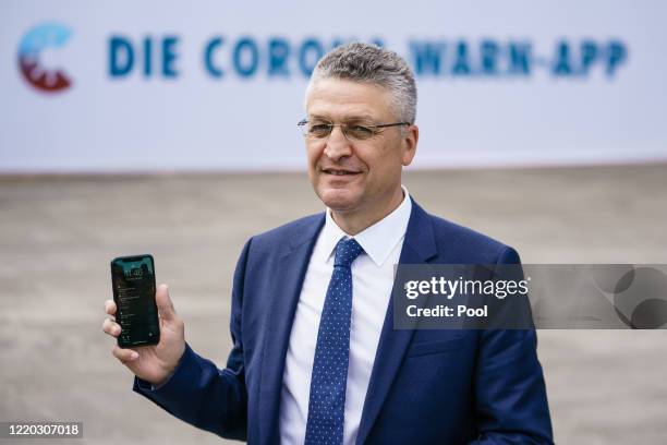 Head of the Robert Koch Institute Lothar Wieler poses for photographers with a smartphone after a press conference during the launch of Germany's...