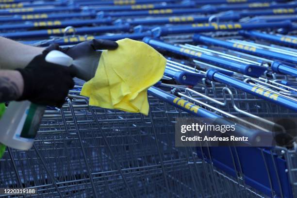 An employee desinfechts the handle on a shopping cart at the IKEA home furnishings store Koeln-Godorf on April 22, 2020 in Cologne, Germany. The...