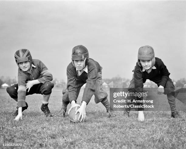 1940s 3 boys in scrimmage line wearing football helmets ready to start play