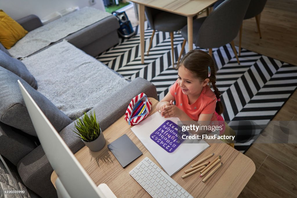 Diligent pupil having conversation with her teacher during online lesson