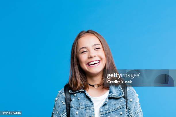 vrolijk mooi tienermeisje op blauwe achtergrond - girl smiling stockfoto's en -beelden