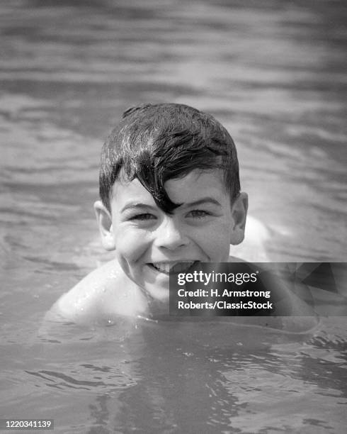 1950s wet smiling boy head above the water swimming looking at camera