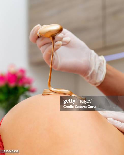 pouring golden wax on young woman's hip - stock photo - leg waxing stock pictures, royalty-free photos & images