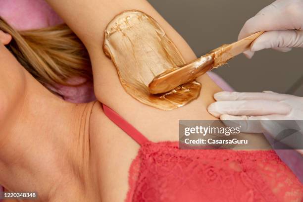 beautician applying wax on woman’s armpit - photo stock - sous le bras photos et images de collection