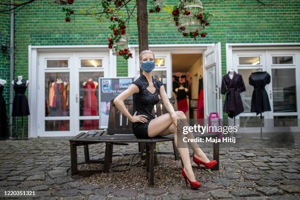 Store mannequin with a protective mask stands before a clothes store as they open for the first time since March during the novel coronavirus...