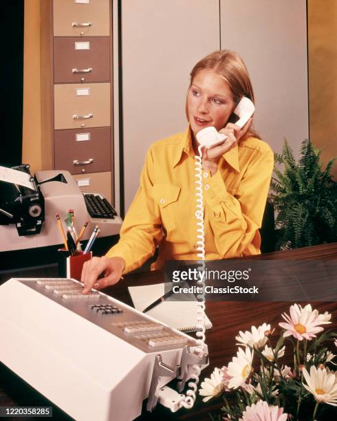 1970s blonde receptionist yellow blouse answering phone pressing button on telephone switchboard console daisy arrangement