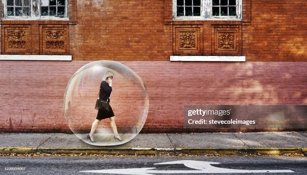 Una mujer de negocios en una burbuja caminando por la acera.