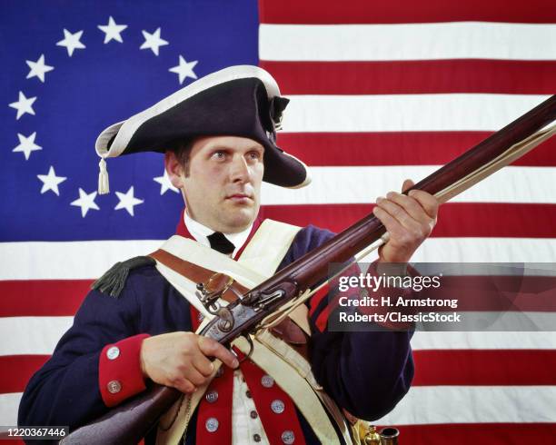 1970s man dressed as colonial continental soldier re-enactor of the american revolutionary war colonial flag in background