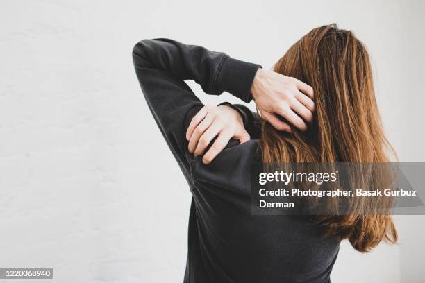rear view of a woman holding her shoulder because of shoulder pain - man touching shoulder stock-fotos und bilder